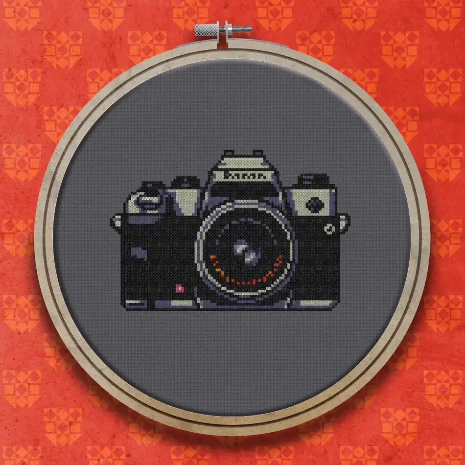 Vintage SLR film camera with a dark body, silver top plate, large round lens and small viewfinder, shown on a white background
