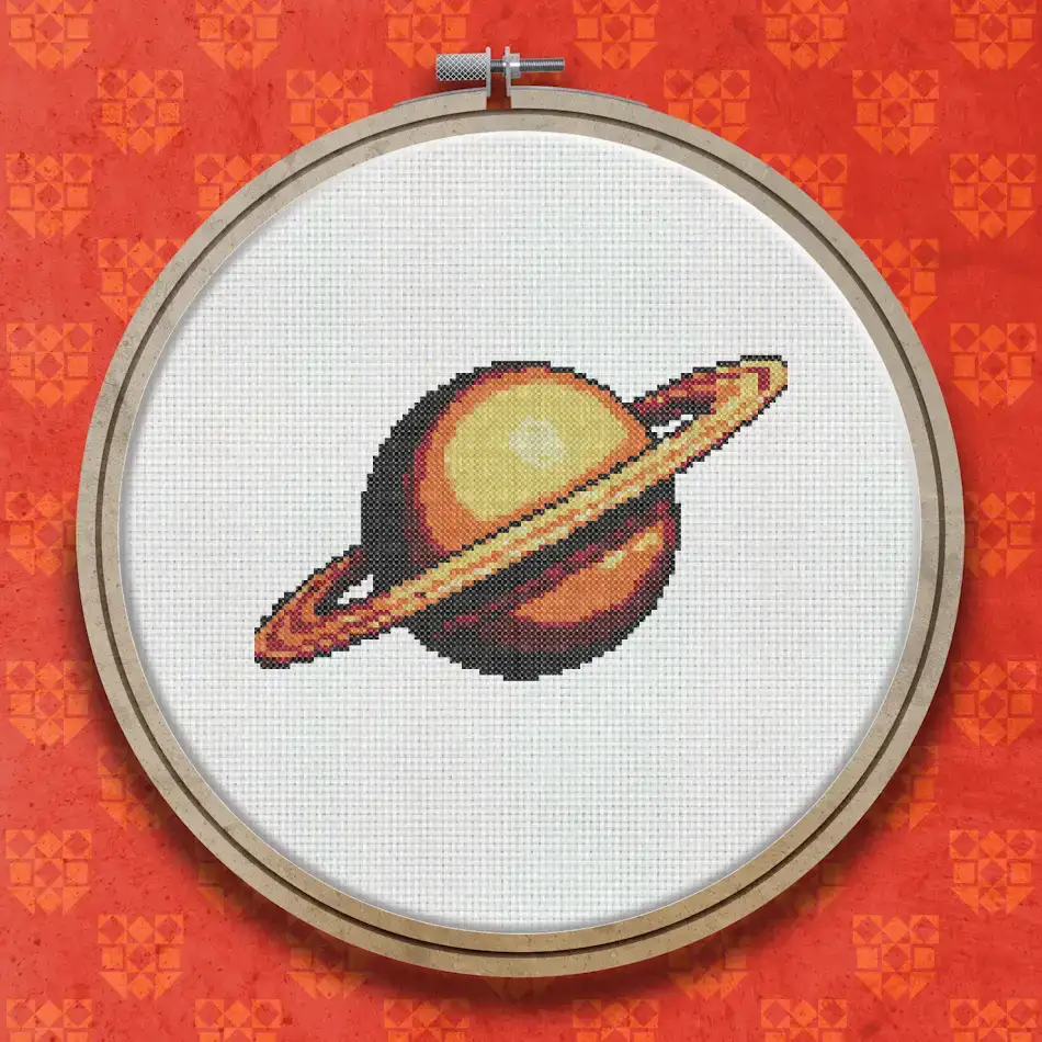 Cross stitch design of Saturn shown as a deep orange planet with a flat golden ring circling its middle, set against a plain background.
