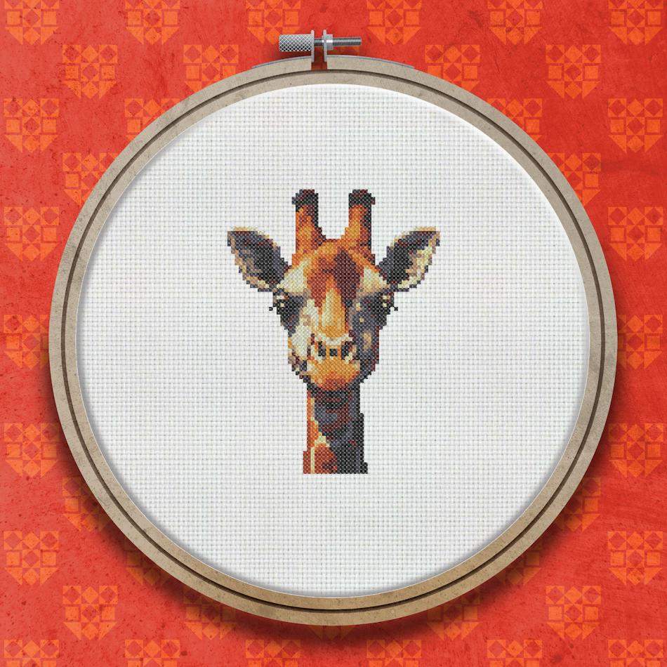 Cross stitch portrait of a giraffe face and neck showing orange and brown patch markings on a light background