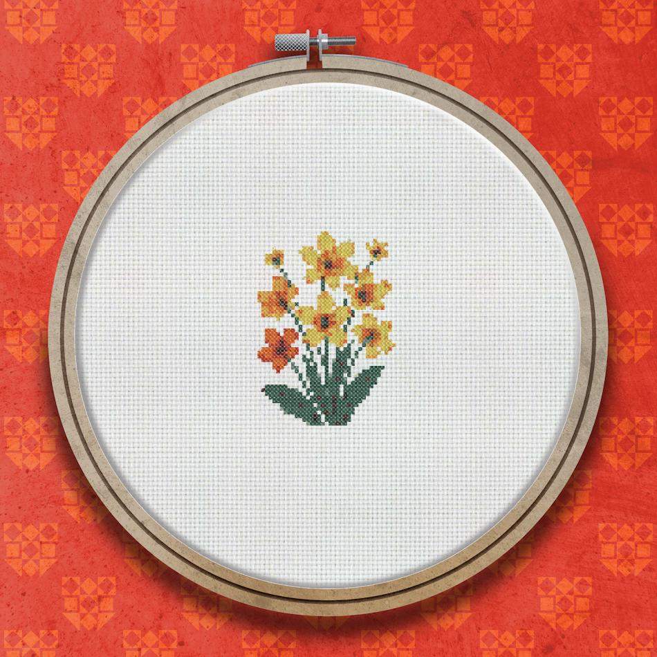 Cross stitch design of a cluster of bright orange flowers with yellow centres and green stems and leaves on a white background.