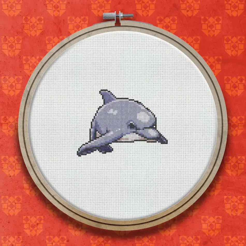 Cross stitch dolphin in blue-grey tones shown in a rounded, compact pose against a white background.