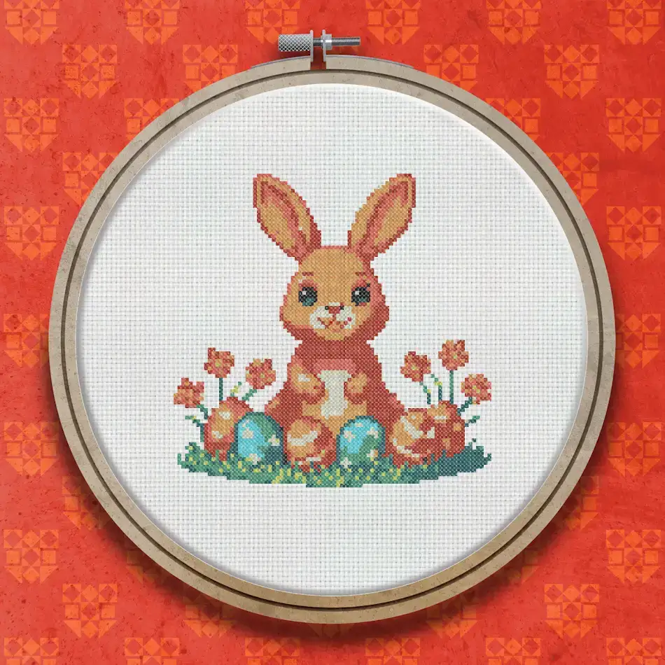 Cross stitch pattern of a smiling brown bunny sitting among colourful Easter eggs and red spring flowers on a white background.