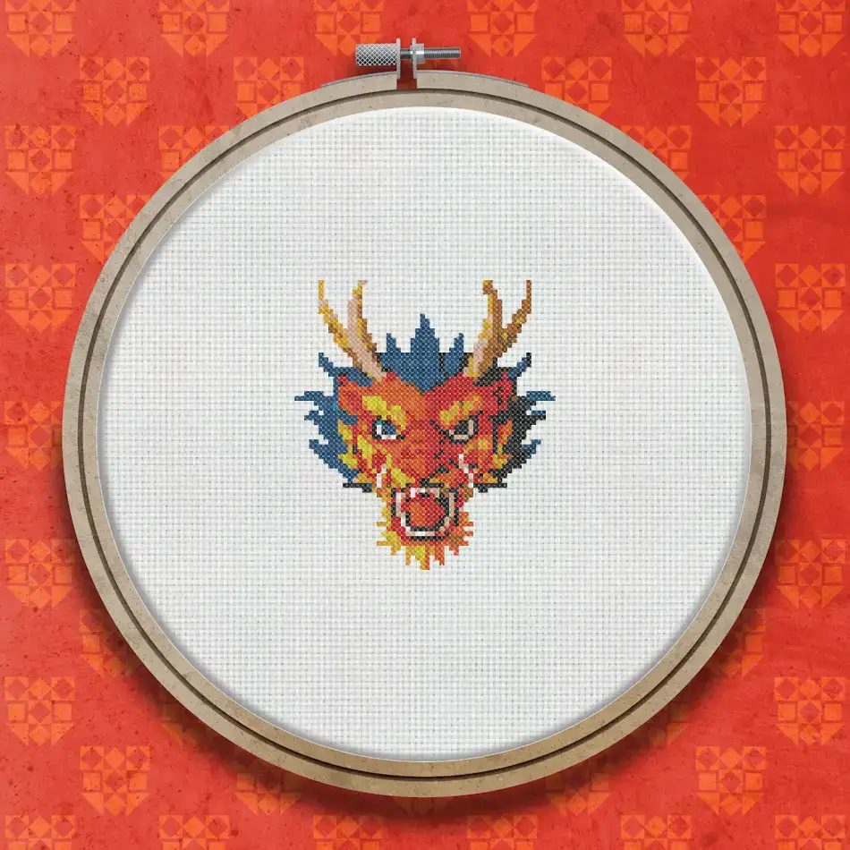 Cross stitch pattern of a red Chinese dragon face with golden horns, orange and yellow flame details, and dark outlining on a white background.