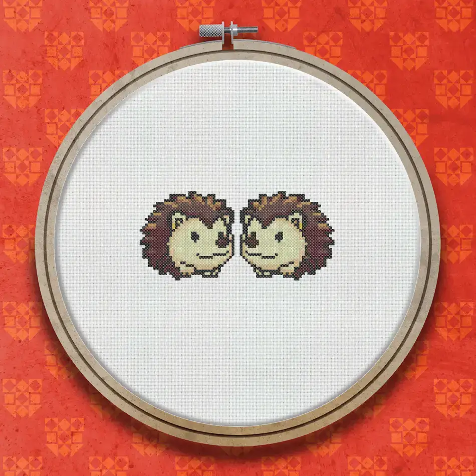 Two small hedgehogs sitting side by side, stitched in brown and cream tones with dark eyes and spiny backs, on a white background.