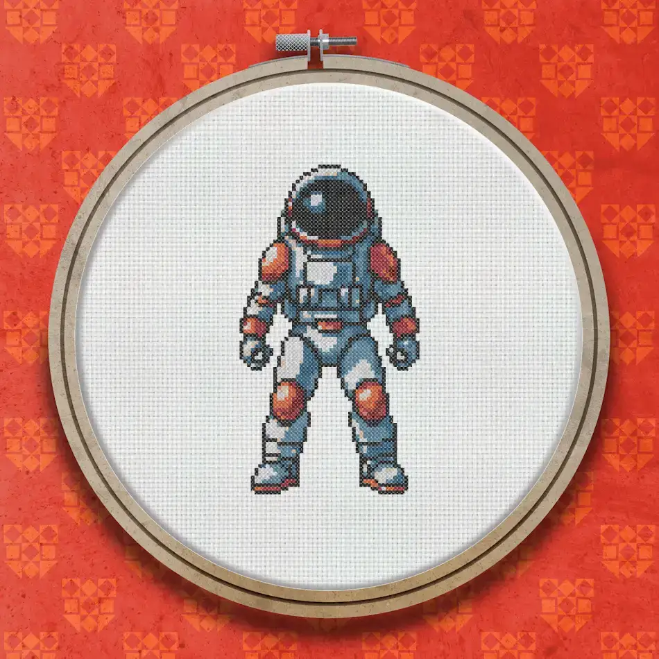 Cross stitch pattern of an astronaut in a white and orange spacesuit with a domed helmet, standing upright against a plain background.