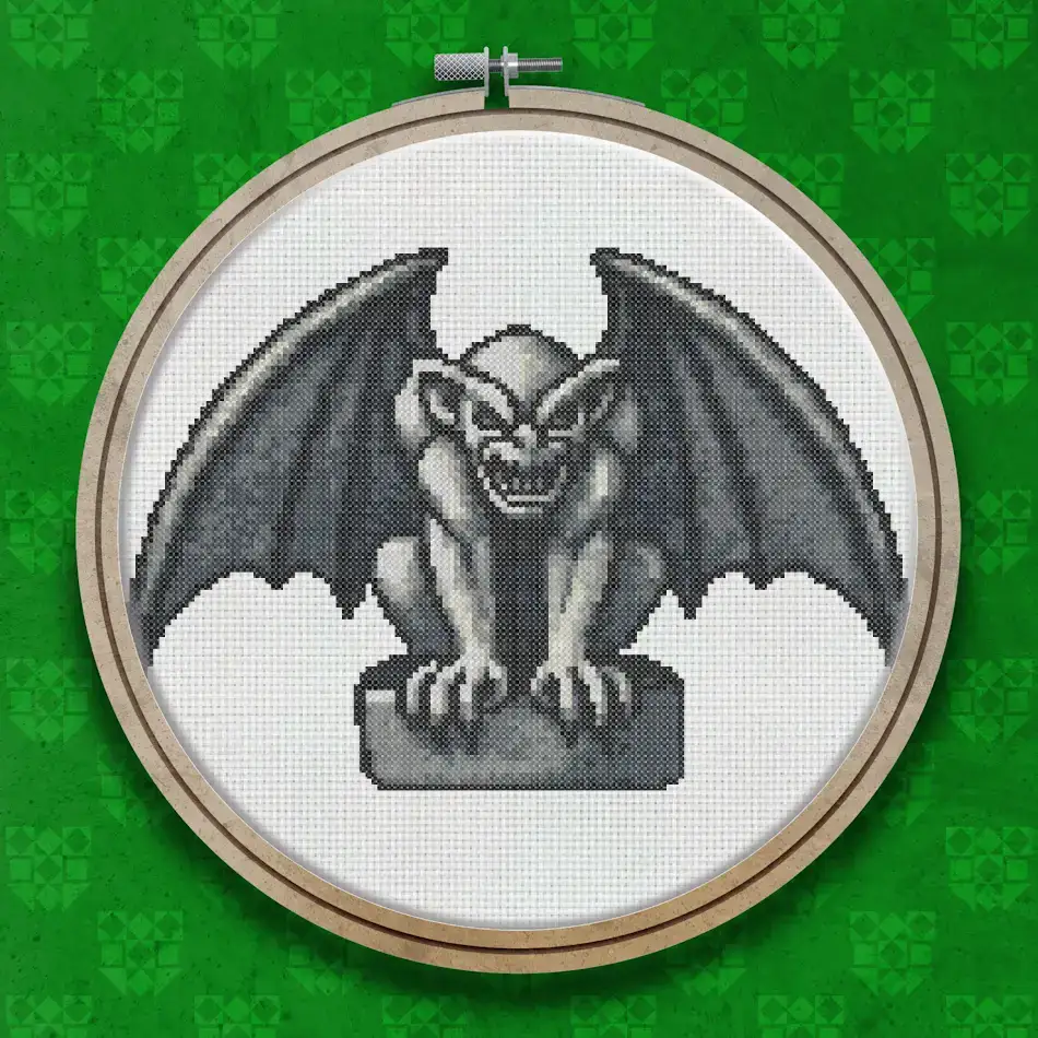 Cross stitch gargoyle crouching on a stone plinth with wings spread, rendered in shades of grey, with a snarling expression and clawed hands.