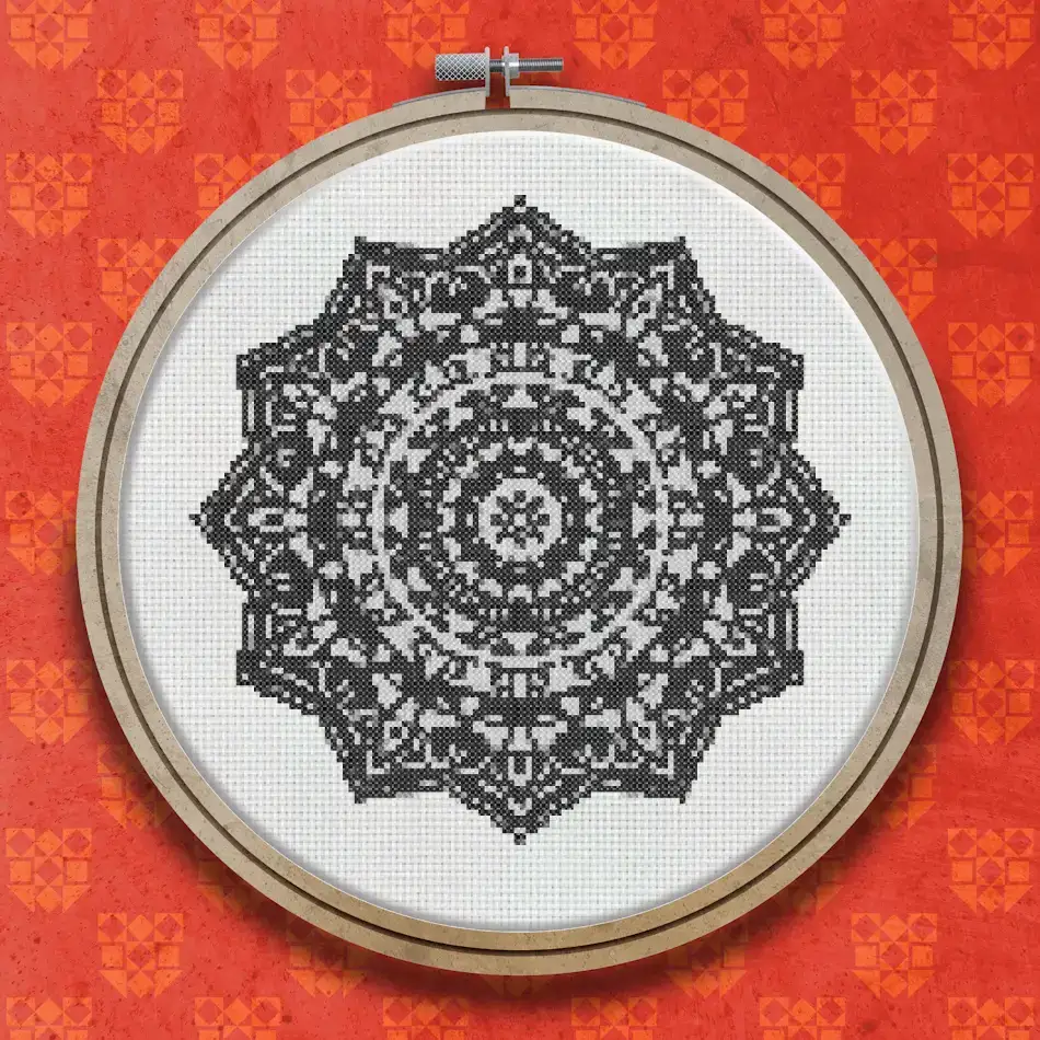 A circular mandala cross stitch design in black and white featuring concentric layers of intricate geometric and floral motifs radiating from a central point.