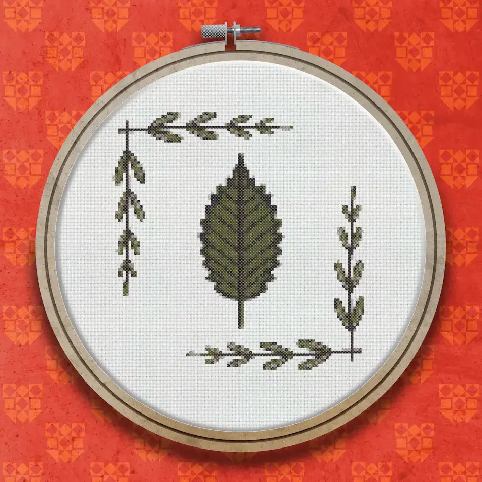Cross stitch pattern showing a large detailed elm leaf in the centre flanked by two vertical sprigs of small leaves on either side, all in shades of dark green.