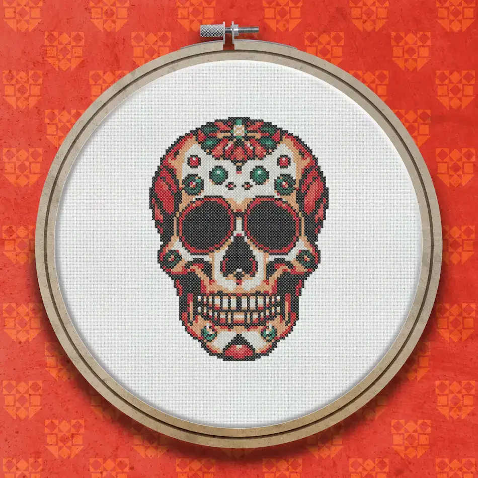 A symmetrical Day of the Dead sugar skull with red, orange and yellow floral and swirl decorations on a white background, with dark eye sockets.