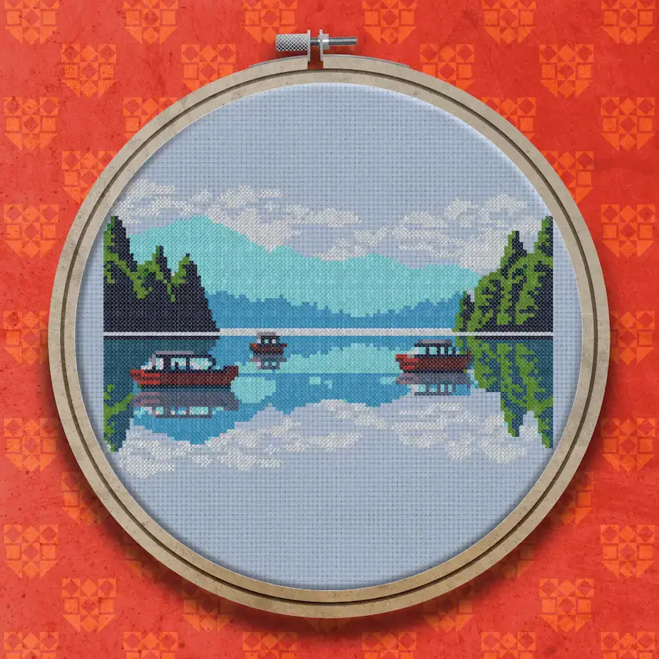 Three small boats on a still lake with pine trees at each side, hazy blue mountains behind and reflections in the water