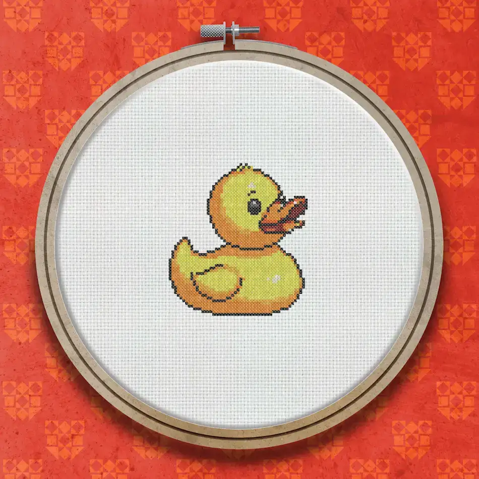Cross stitch pattern of a bright yellow rubber duck with an orange beak, small wing detail, and a cheerful expression on a white background.