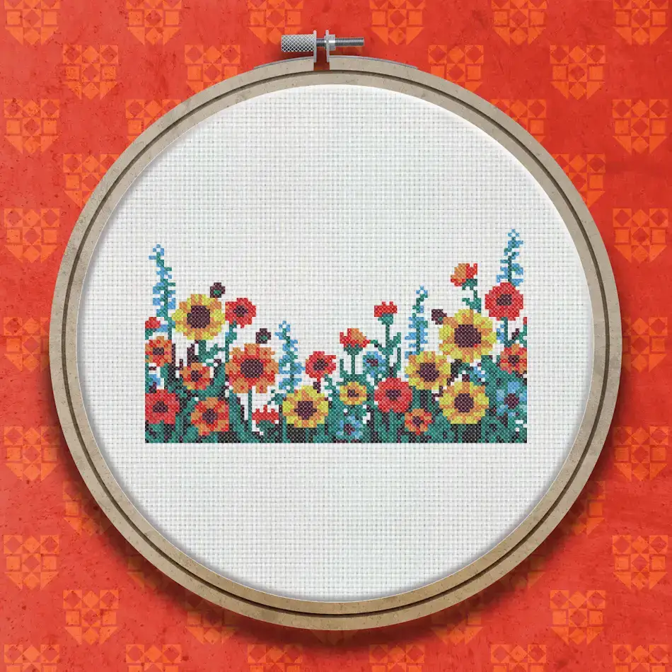 Cross stitch border design featuring red, orange, and yellow flowers including sunflowers and poppies with green stems and blue accents on a white background.