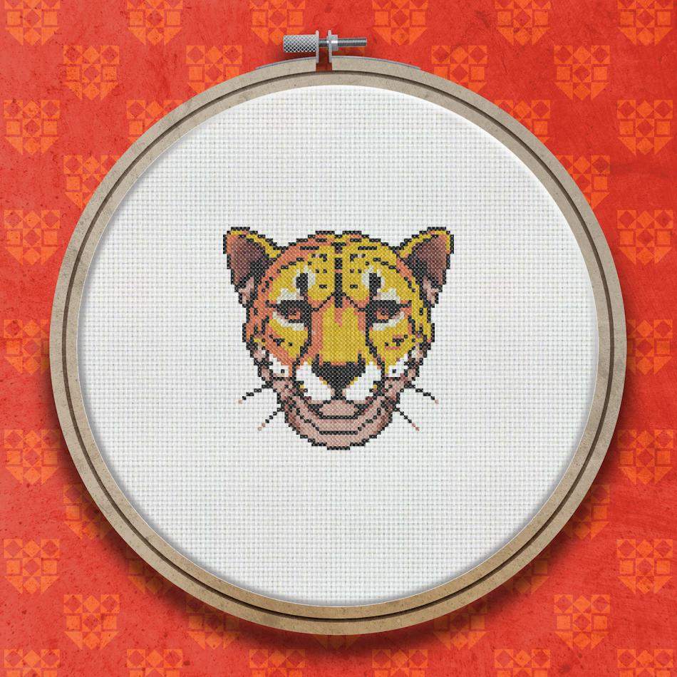 Cross stitch portrait of a cheetah face with golden fur, dark spots, green eyes, and a cream muzzle on a plain background.