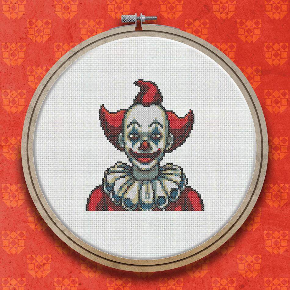 Cross stitch design of a clown with a red and white ruffled collar, red hat, painted smile, and rosy cheeks on a dark background.
