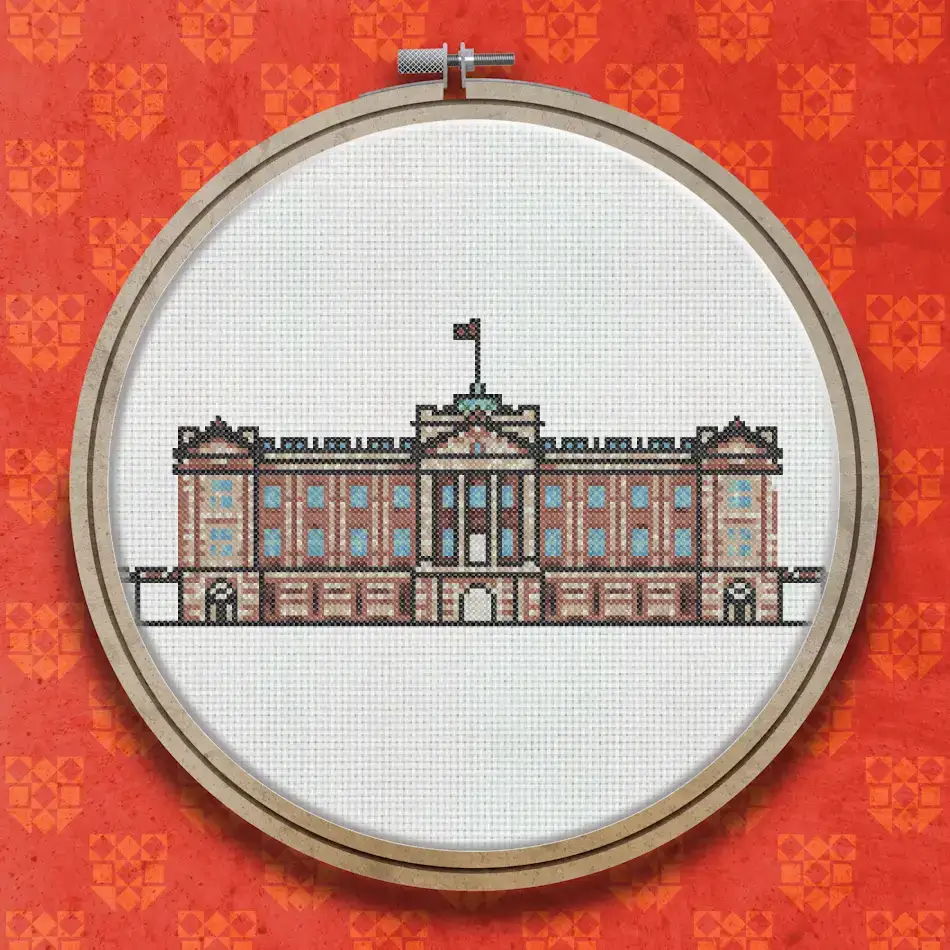 Cross stitch design of Buckingham Palace showing a wide symmetrical neoclassical facade with columns, arched windows, a central entrance, and a flag on the roofline.