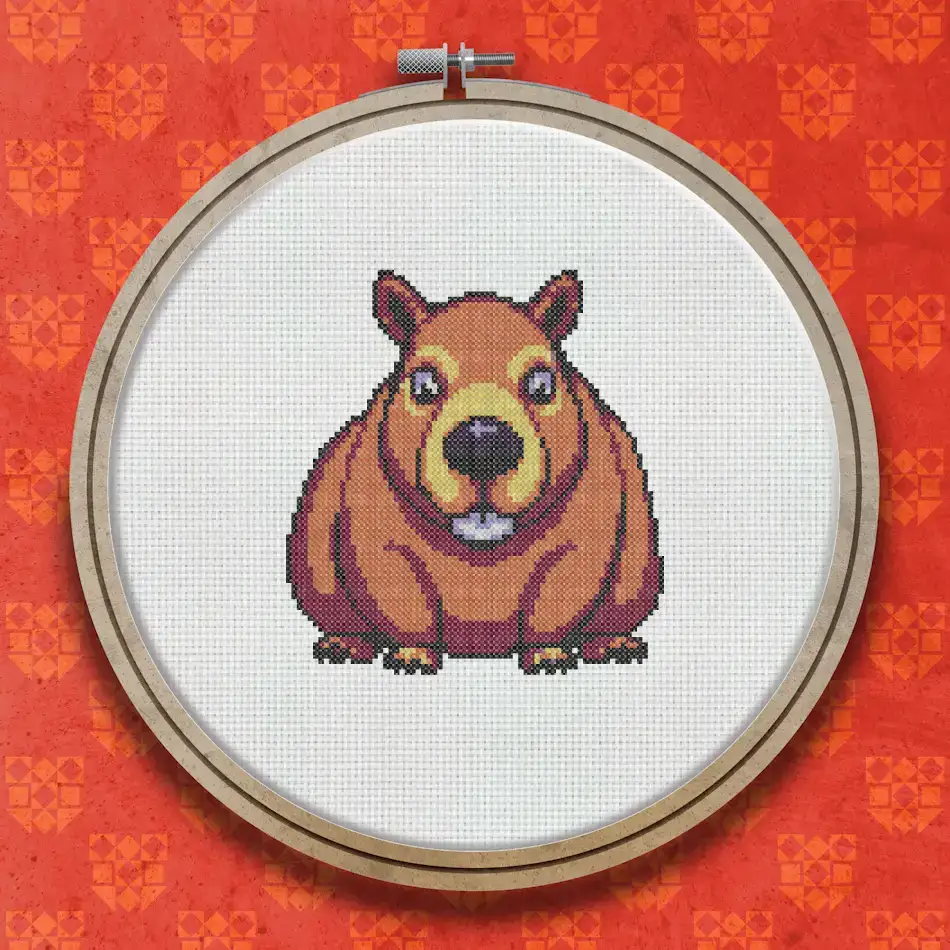 Cross stitch design of a smiling capybara with a round brown body, large front teeth, rosy cheeks, and a cheerful expression on a white background.