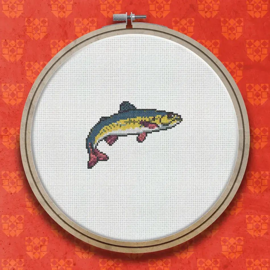 Cross stitch pattern of a trout shown in profile, with an orange-brown body, dark speckled markings, and a curved tail fin.