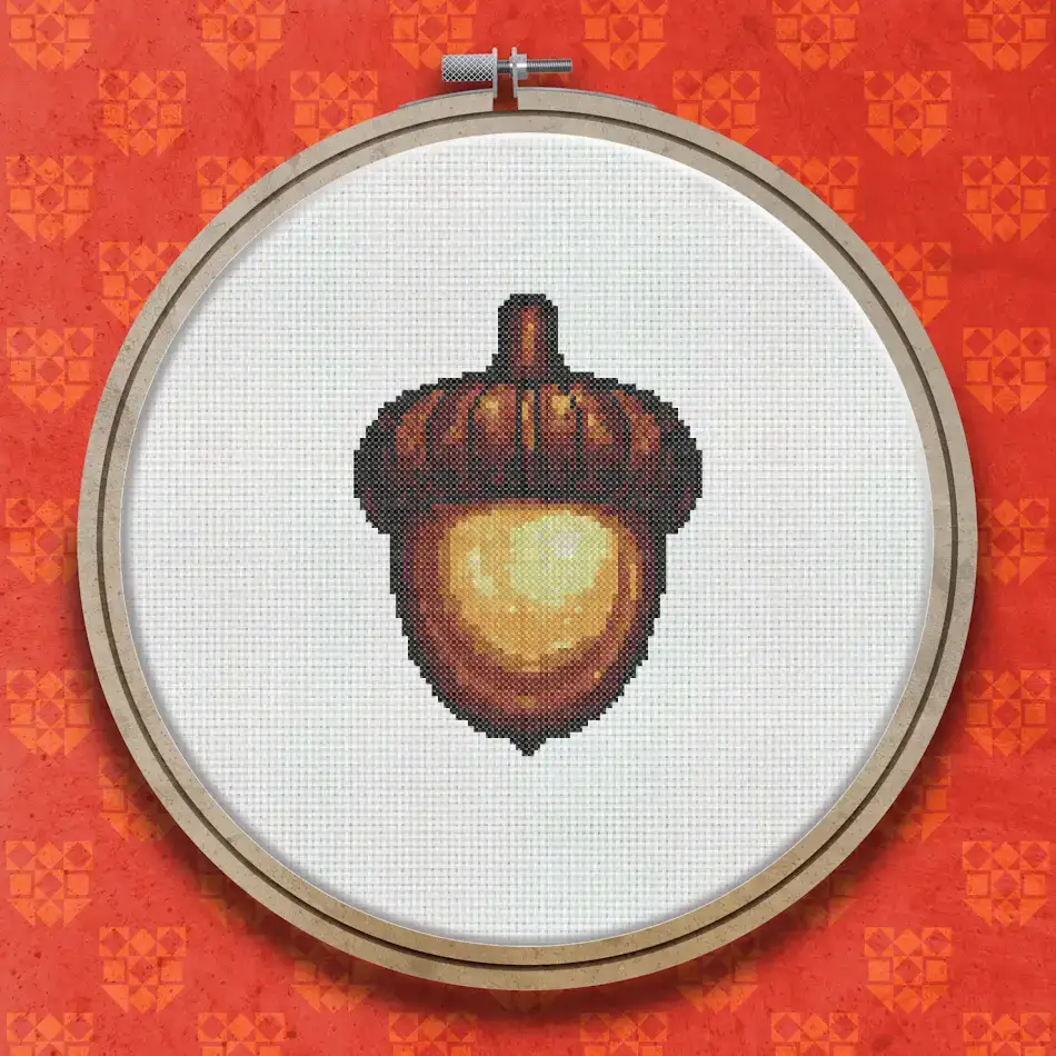 Cross stitch pattern of a single acorn with a golden-brown oval body and a darker textured cap with a short stem.
