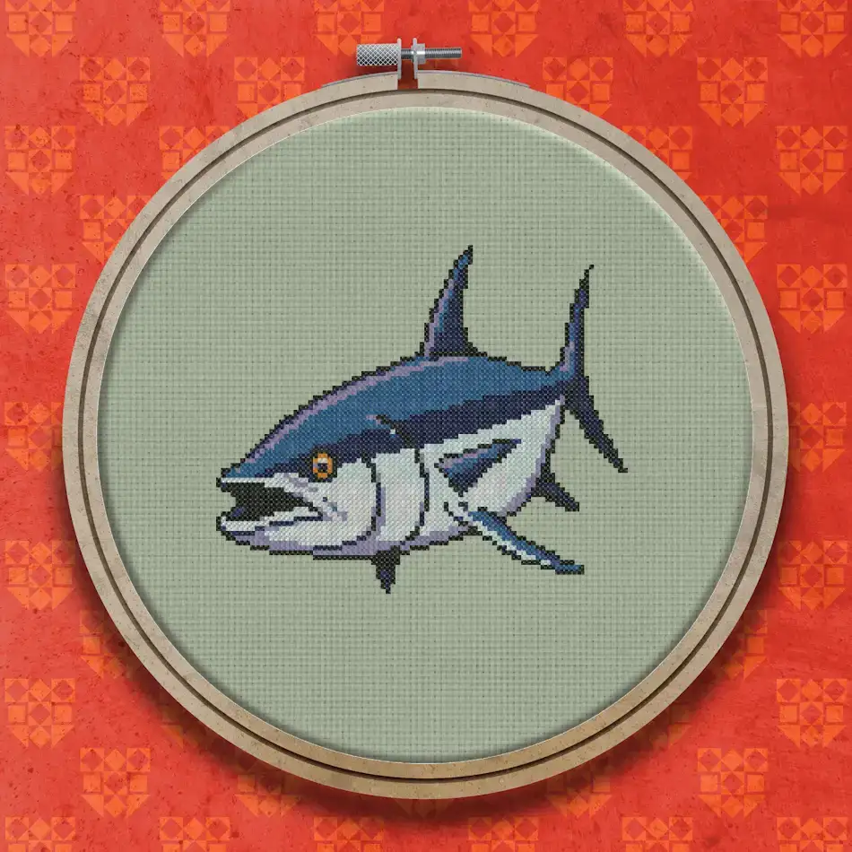Cross stitch design of a large tuna fish swimming left, shown in deep blue and silver tones with a white belly and dark eye.