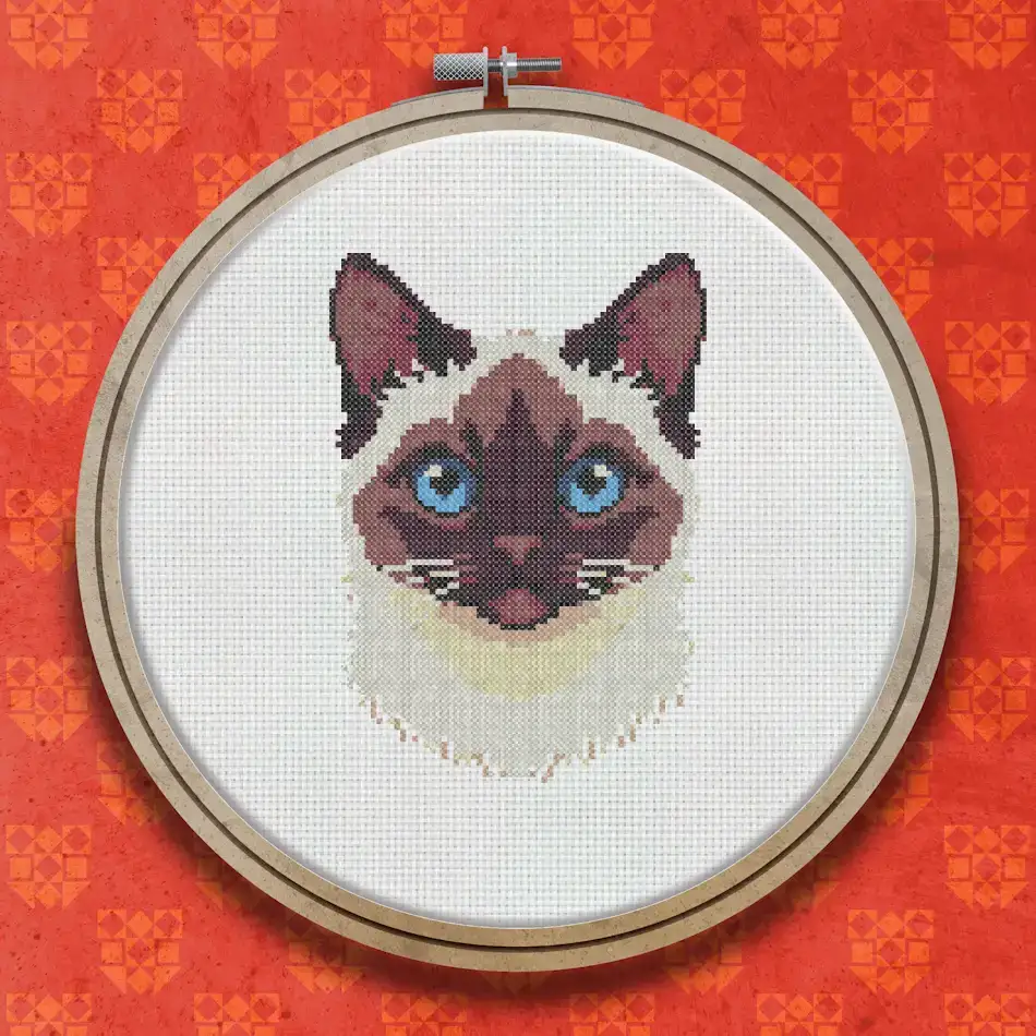 Cross stitch portrait of a Birman cat with cream and seal-point fur, a light face and vivid blue eyes on a white background.