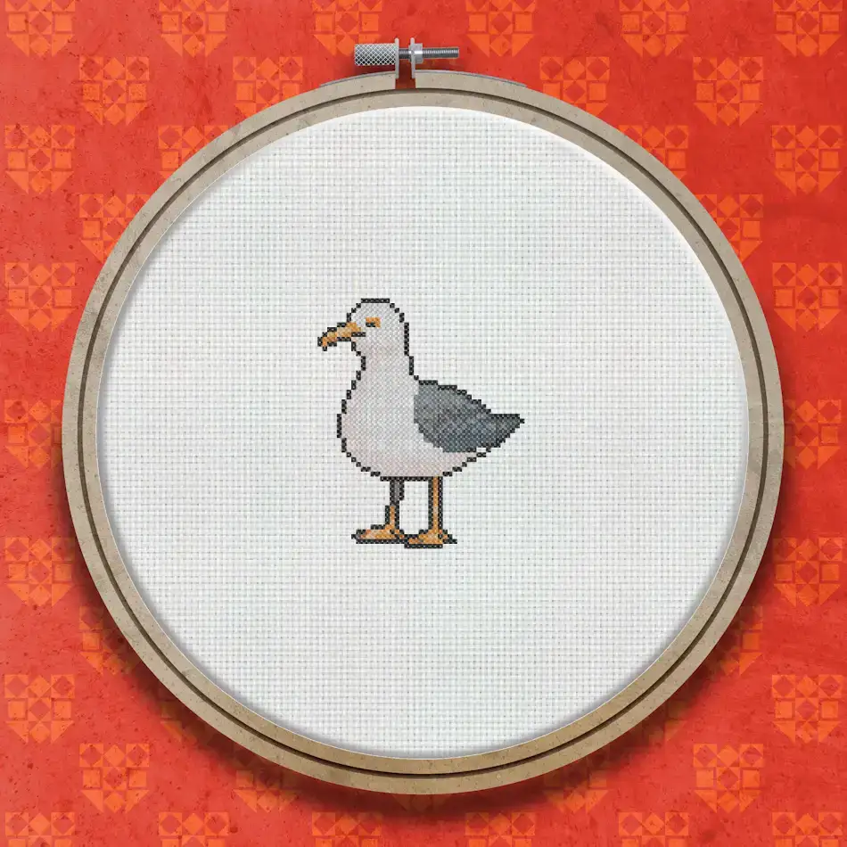 Cross stitch design of a seagull with white body, grey wings, orange beak and legs, standing upright against a plain background.