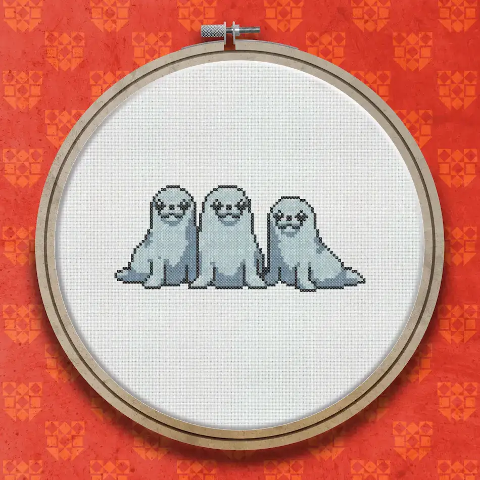 Cross stitch pattern of three grey seals sitting side by side, depicted in soft shades of grey and white against a plain background.