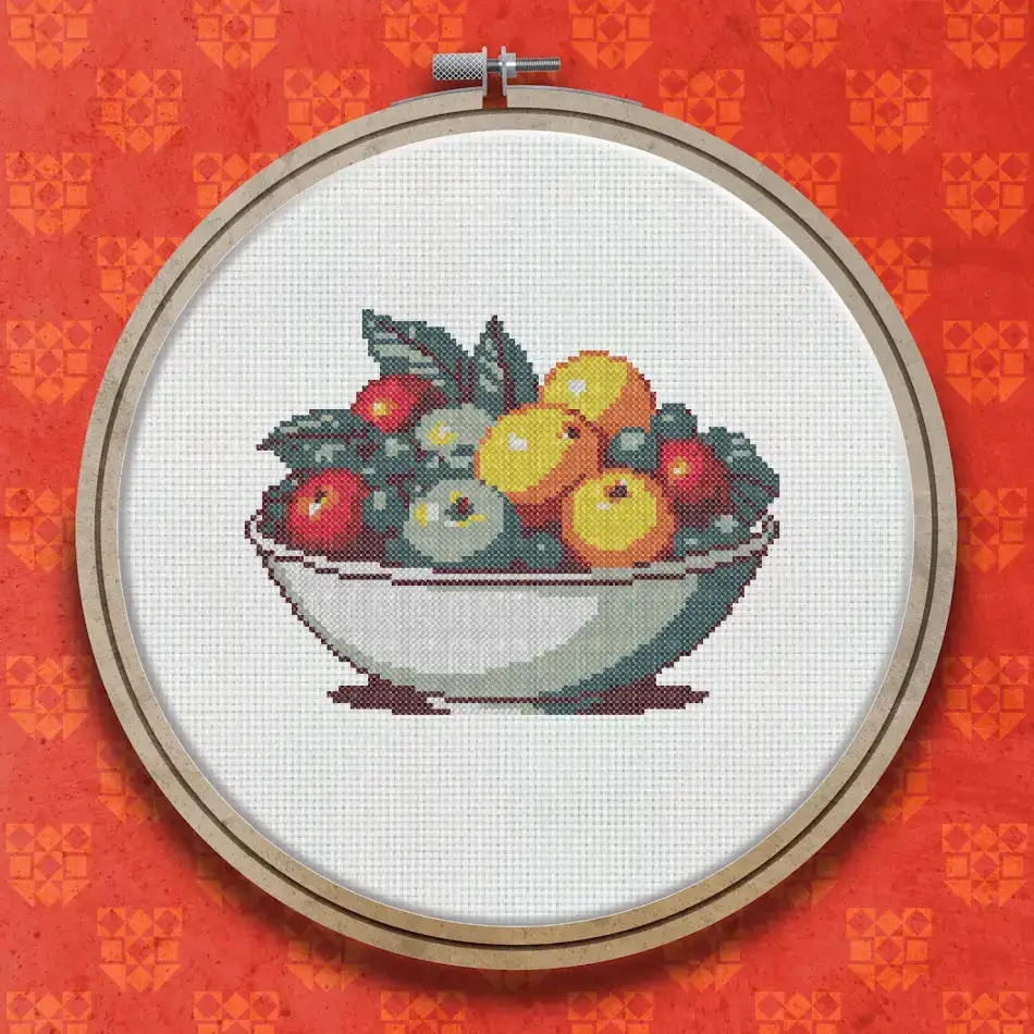 Pixel art style cross stitch design of a white bowl filled with red apples, orange and yellow citrus fruits, and teal and purple round fruits.
