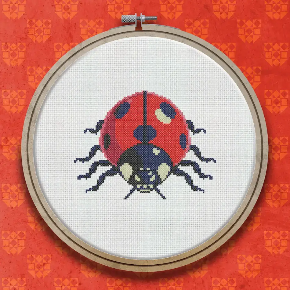 Cross stitch design of a red ladybird with black spots, a dark head, and six black legs, viewed from above against a white background.