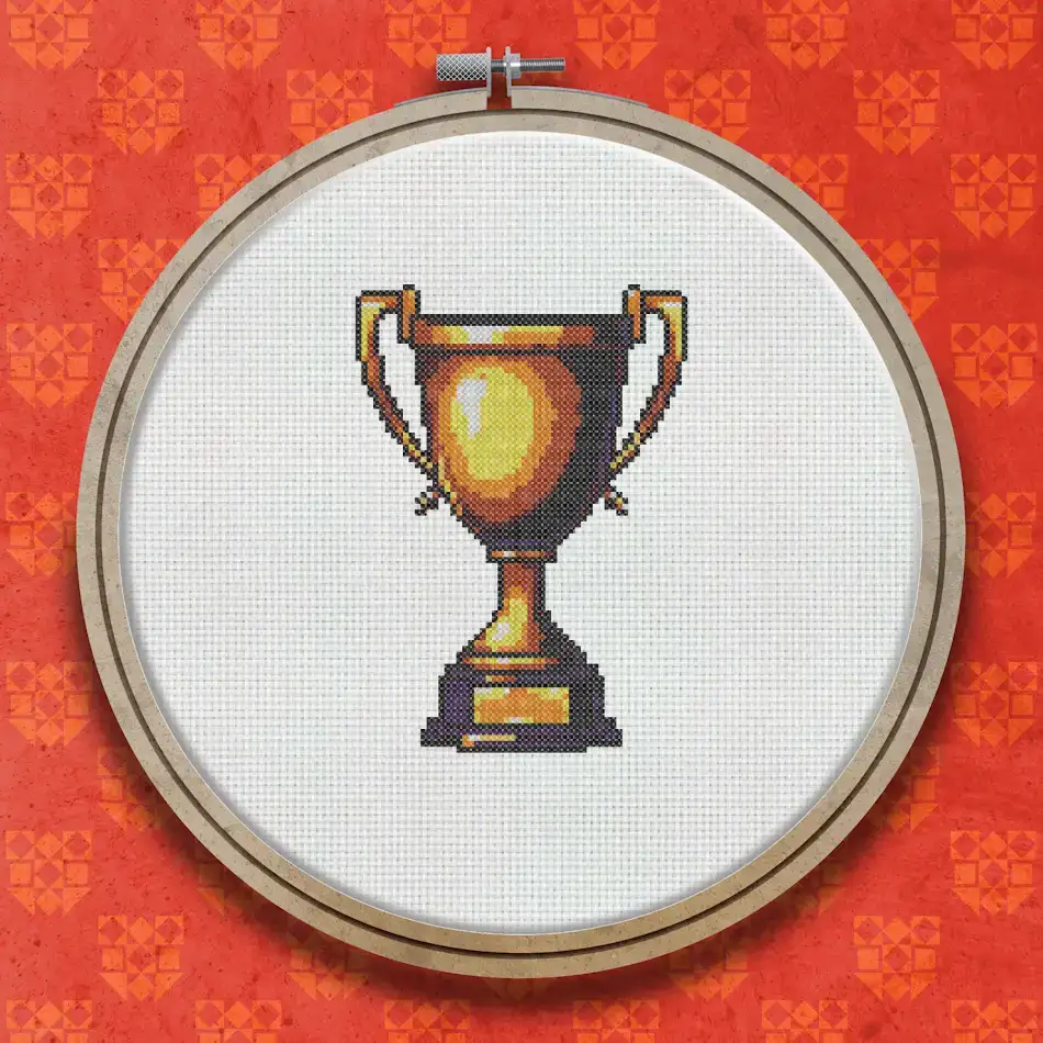 Cross stitch pattern of a gold trophy cup with a wide bowl, two handles, and a stepped rectangular base in shades of amber and brown.