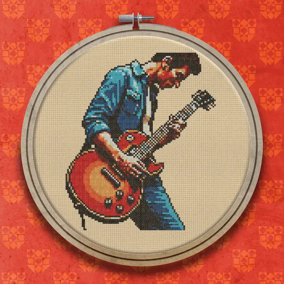 Cross stitch design of a male guitarist in a blue denim jacket playing a red sunburst electric guitar, angled to the right.