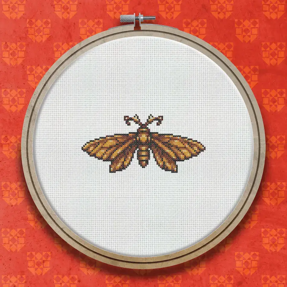 Cross stitch pattern of a moth with spread wings in warm amber, orange and brown tones with detailed symmetrical wing markings.
