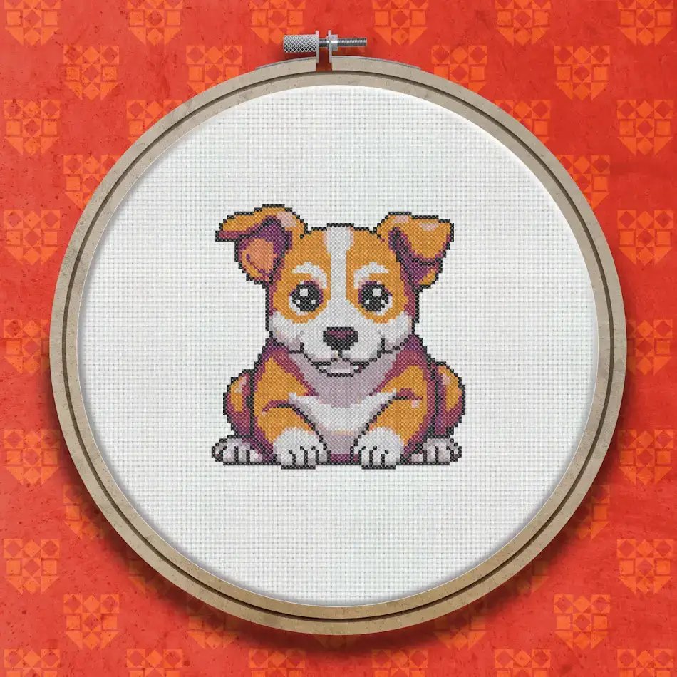 Cross stitch pattern of a small brown and white puppy sitting upright with a happy expression, worked in warm tan, rust and cream tones.