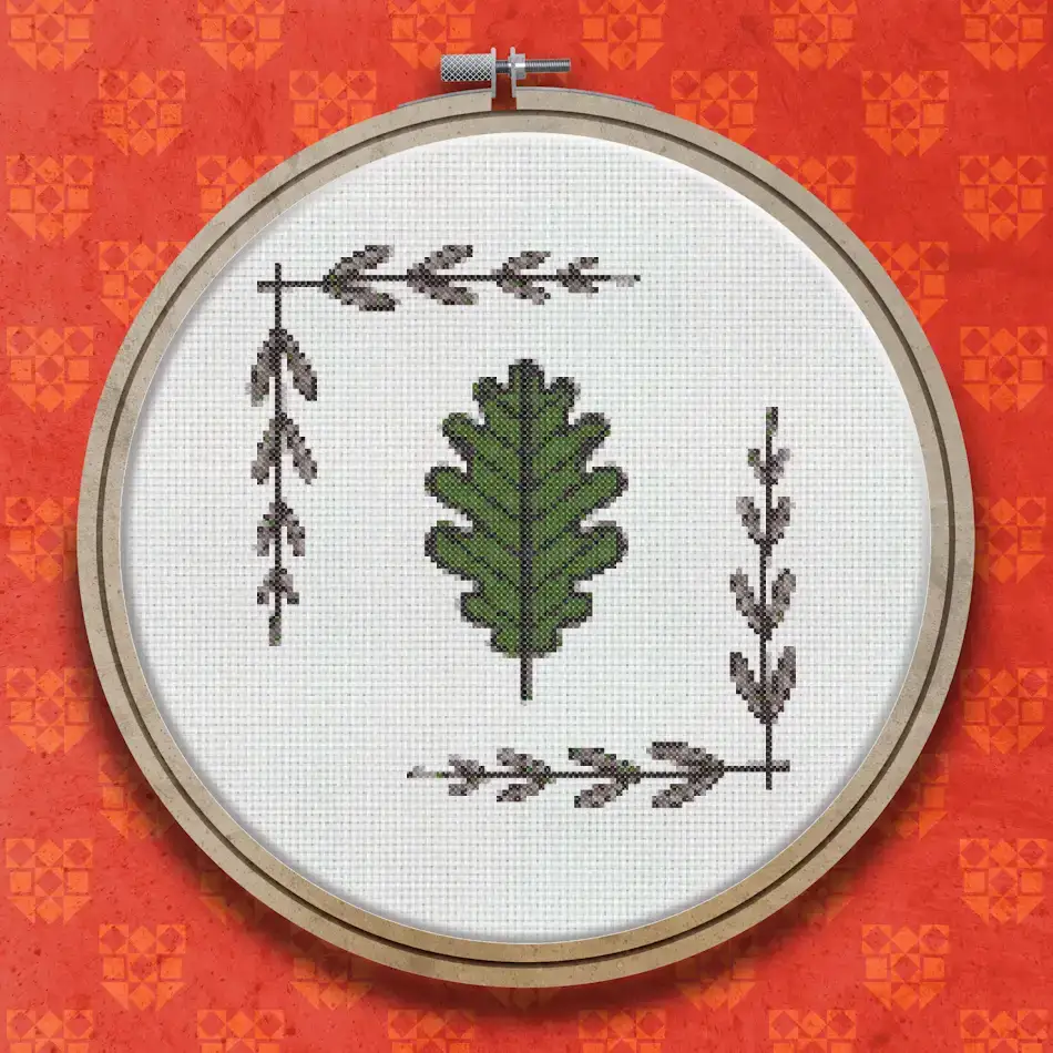Cross stitch pattern showing a large green oak leaf in the centre surrounded by four corner sprigs of small pointed leaves in dark green and brown.