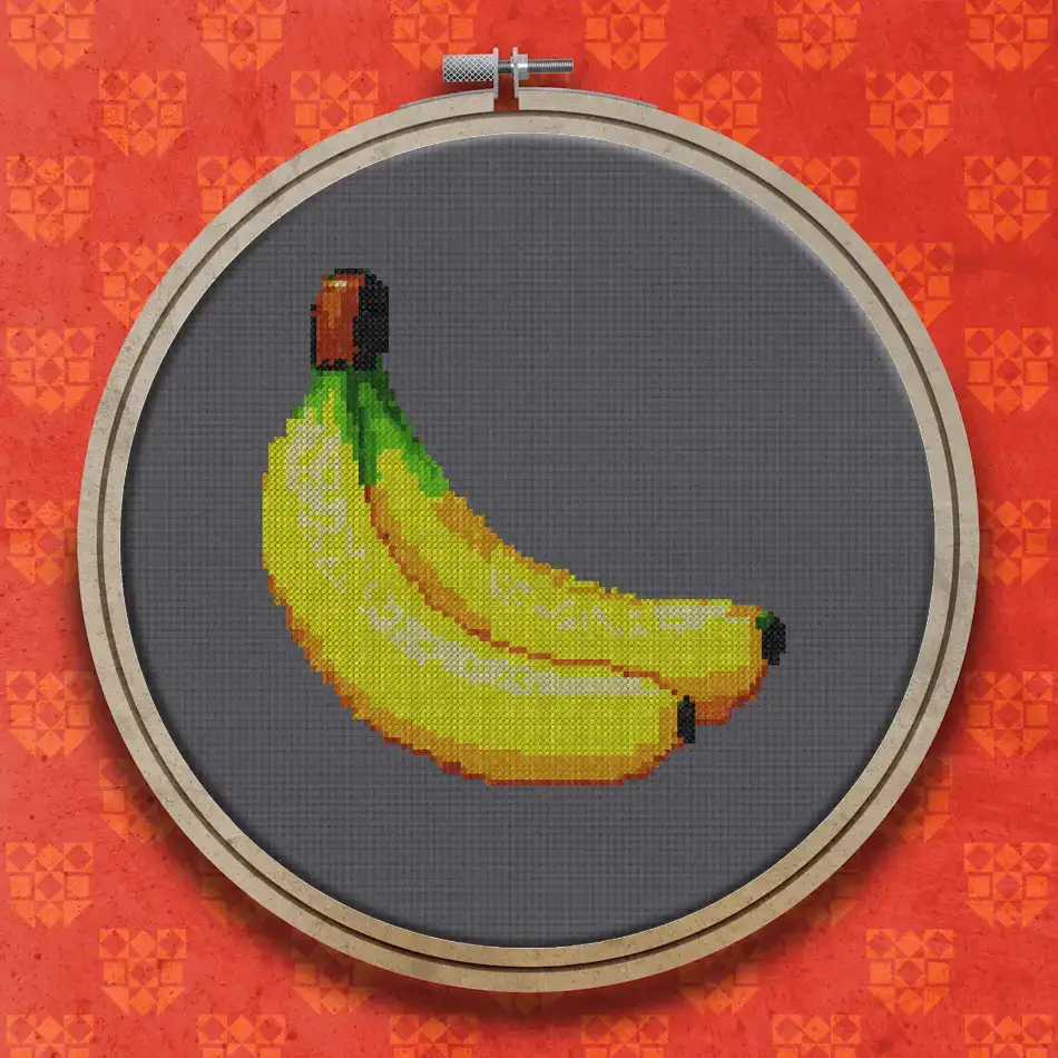 Cross stitch design of two ripe bananas joined at the stem, shown in bright yellow with subtle green and shaded detailing.