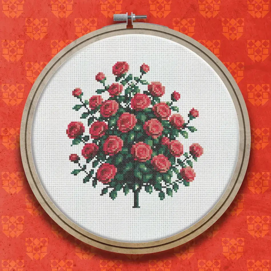 Cross stitch design of a round rose bush with red blooms and green leaves on a slender brown trunk against a white background.