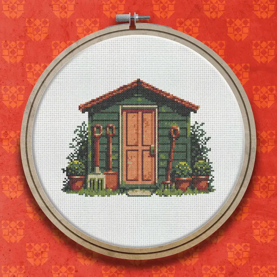 Cross stitch design of a green wooden garden shed with a brown door, potted plants and red flowers arranged around the entrance.